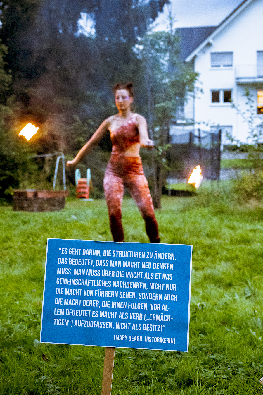 Szenenfoto aus SUPER BADASS WOMEN, eine Schauspielerin spielt mit Feuerpois in einem Garten