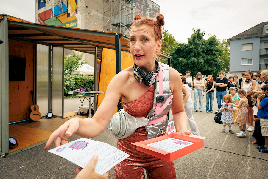 Szenenfoto aus SUPER BADASS WOMEN, Schauspielerin verteilt Bullshitbingo- Zettel
