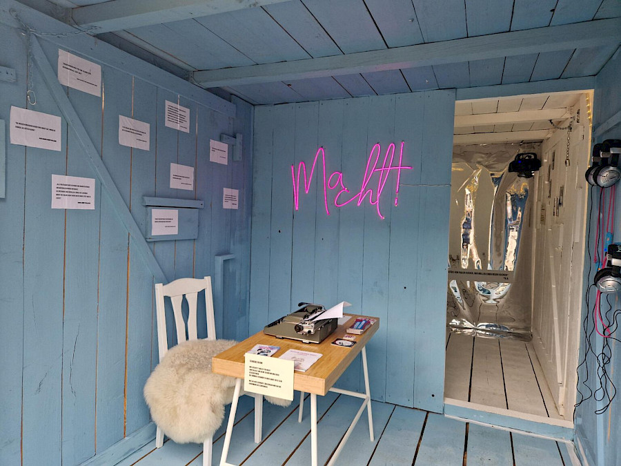Innenansicht alter, kleiner Container mit Blick auf das leuchtende "Macht"- Schild